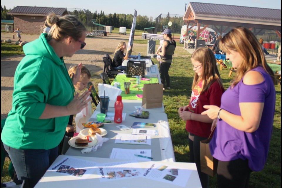 Amanda Cull, club leader for the Lac La Biche 4-H club, tells Lucy Theroux and her daughter, Alyssa Theroux, about the organization during the 2023 Let's Connect Information Fair. Chris McGarry photo.