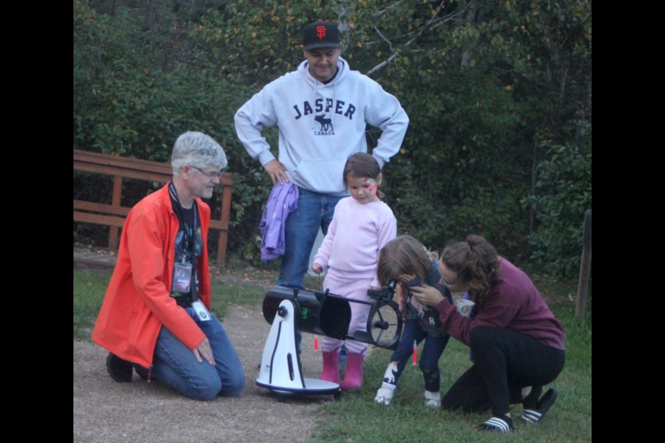 Alister Ling, a member of the Edmonton Chapter of the Royal Astronomical Society of Canada (RASC) shows Kent and Chloe McDonald and Jesse and Lainey Kehr to how watch the sky through the lens of a Dobsonian telescope during the 2024 Lakeland Dark Sky Celebration, which took place on Saturday, Sept. 14 at Sir Winston Churchill Provincial Park. Chris McGarry photo. 