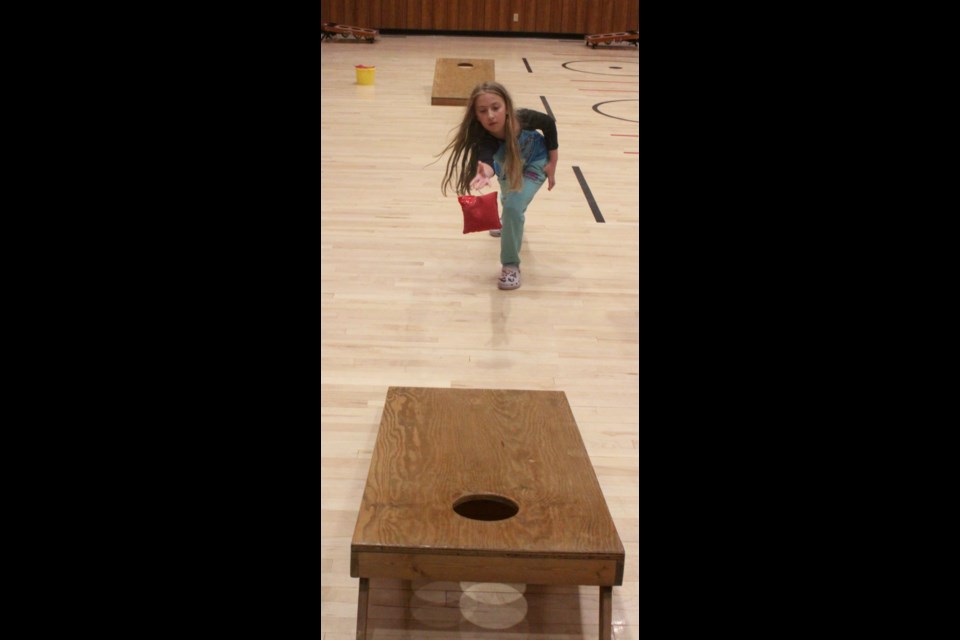 Amira Mamela tries her luck with the bean bag toss game, one of several fun activities set up inside of the Craigend Community Centre for both kids and adults to enjoy. Chris McGarry photo.