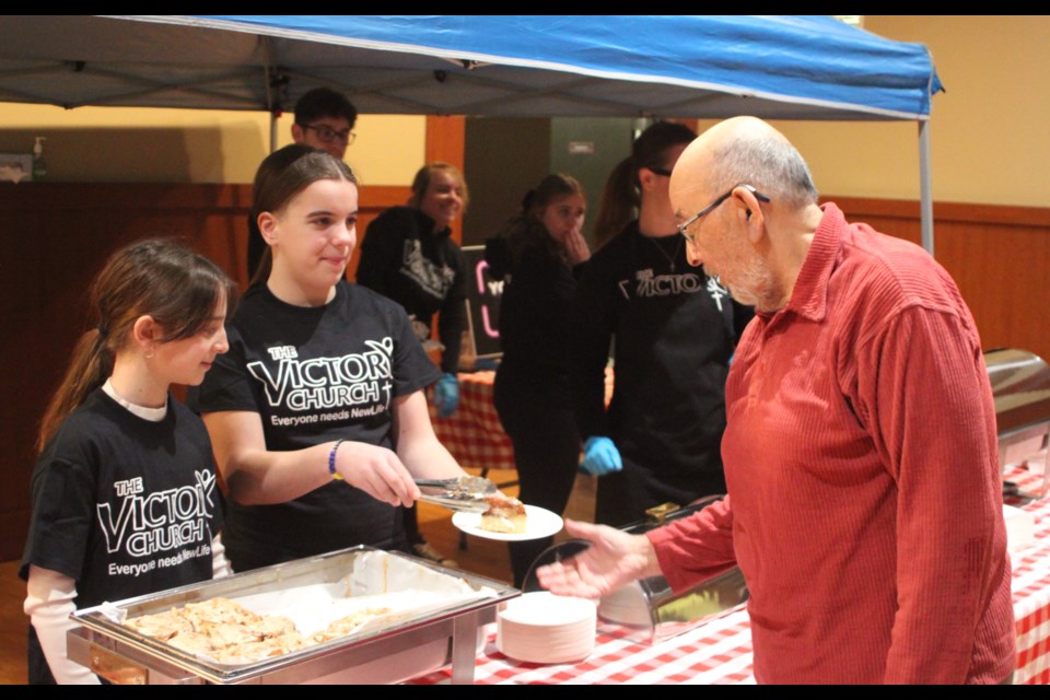 Autumn Boisvert and Asia Flumian were part of the group from New Life Victory Fellowship who were serving fresh cinnamon buns and hot chocolate to people at the Family Day festival held on Feb. 17 at Lac La Biche’s Bold Centre. The youngsters serve a bun to Wally Sinclair. Chris McGarry photo.