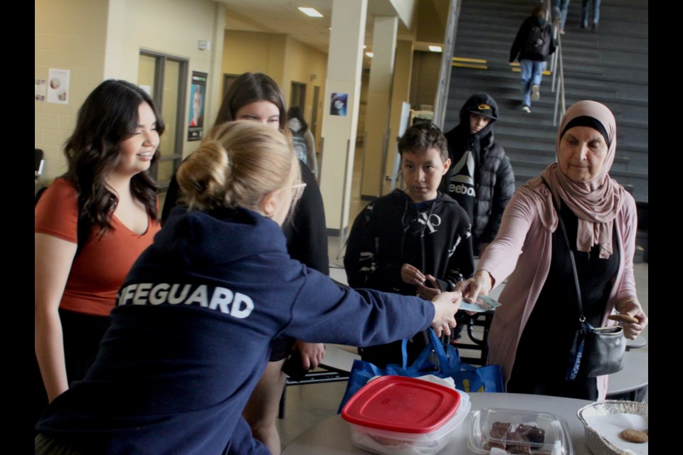 Nouhad Fayad, an educational assistant at JAWS, purchases some baked goodies from Frances Farrant, a Grade 12 student who was helping with the bake sale. Chris McGarry photo.