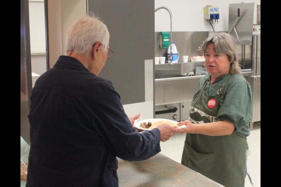 Bev Tkachuk, a member of the Lac La Biche Agricultural Society, serves some pancakes to Leona Glazerman. Chris McGarry photo.