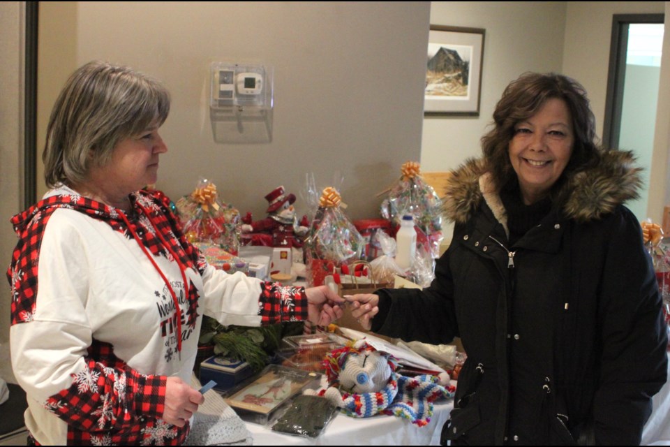 Bev Tkachuk, manager of the Lac La Biche Farmers Market gives a ticket to Stacie Dease for the door prizes that were on offer during the final market of the 2024 season, which took place on Friday, Dec. 13 at the Lakeland Agricom. Chris McGarry photo. 