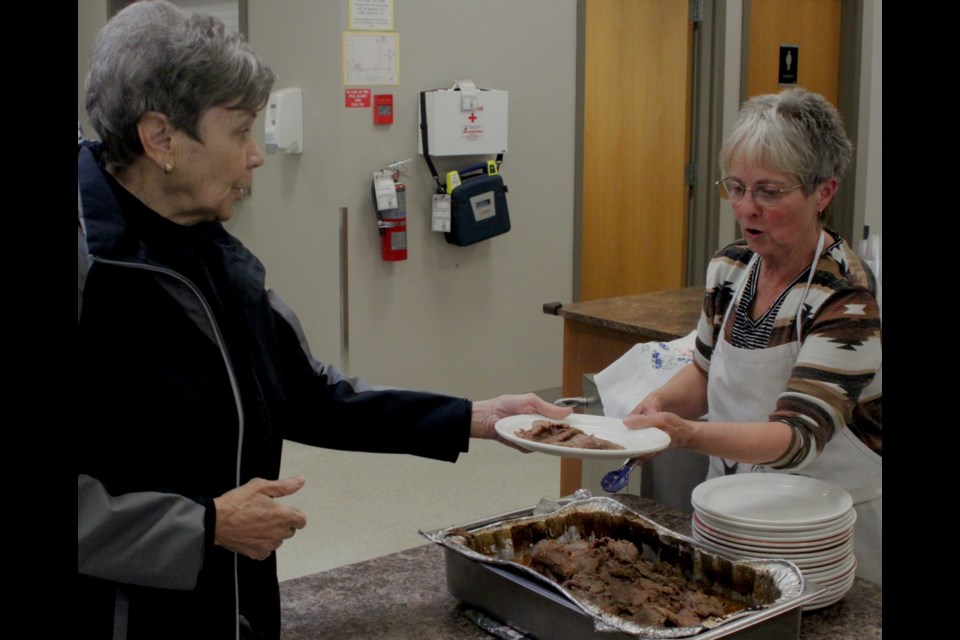 Donna Fabbro serves up some beef to Darlene Tardif during the meal served Wednesday at the Lac La Biche Heritage Centre for Alberta Seniors Week. Chris McGarry photo. 