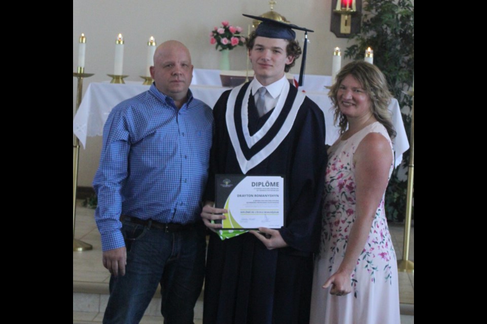 Drayton Romanyshyn stands with his parents, Gary and Sylvia, after receiving his diploma at the graduation ceremony which took place at St. Isidore Catholic Church in Plamondon. Chris McGarry photo. 