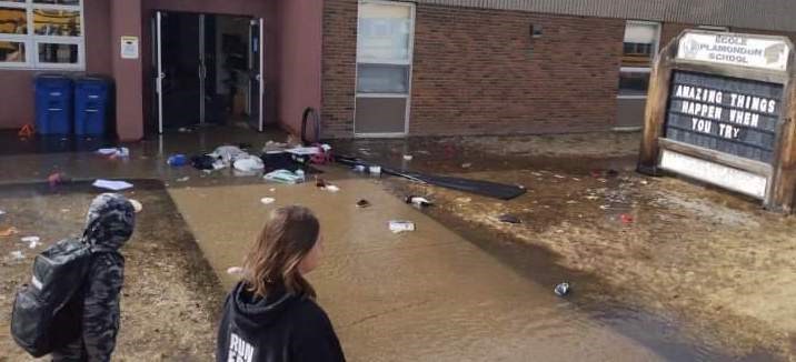 students walk past damage caused by the massive flood that swept through Ecole Plamondon School on April 18. 