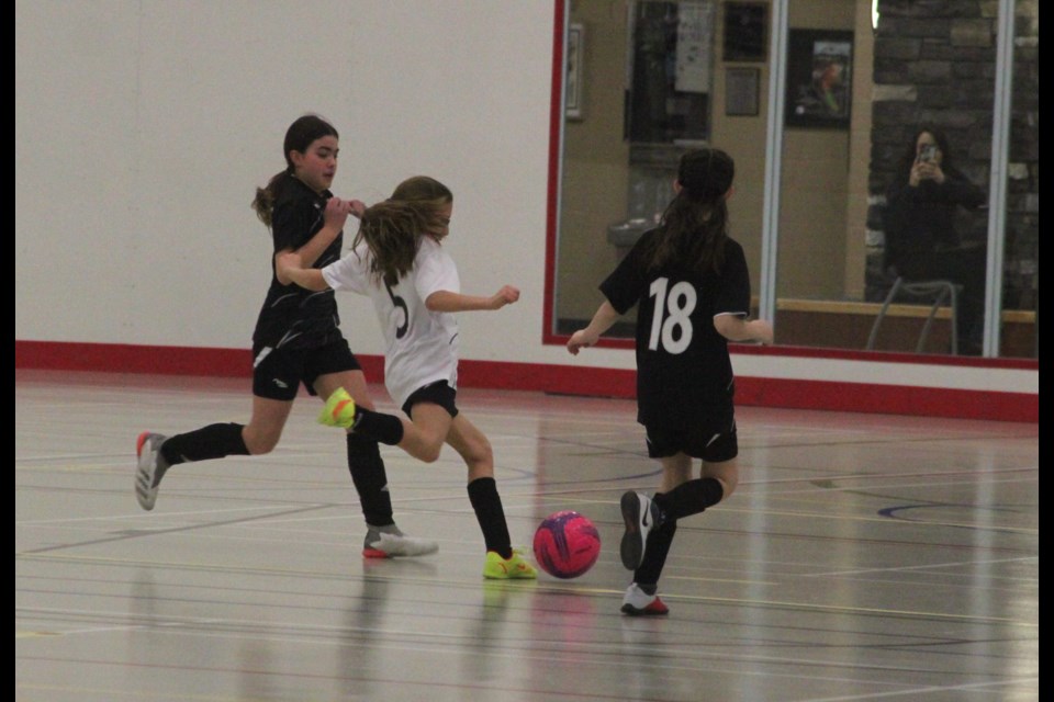 On Saturday, Feb. 1, two Bonnyville U13 girls squads faced each other inside Lac La Biche's Bold Centre during the most recent league weekend. One team (wearing black uniforms) is led by coach Coy Schaub while the other squad (white uniforms), is coached by Sirois Tercier. Ella Kriaski, a member of the Tercier team, is flanked by two opponents as she runs with the ball to the other end of the indoor field. Chris McGarry photo. 