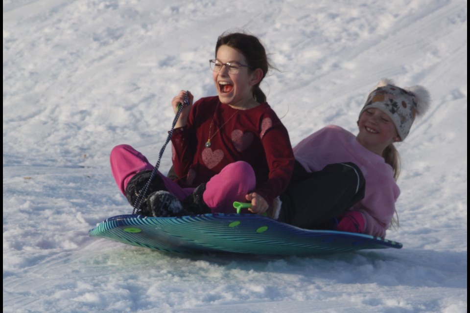 Ellie Trimble and London Miller enjoy the thrill of sliding down the tobogganing hill in Lac La Biche’s Alexander Hamilton Park. Trimble and Miller, along with other youngsters and their families, were at the municipal park on Feb. 22 spending an afternoon sledding. Chris McGarry photo. 