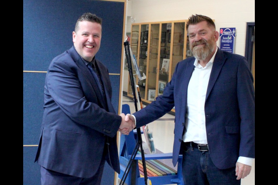 Brian Jean shakes hands and shares a laugh with Etienne Vaillancourt, principal of Ecole Beausejour. Chris McGarry photo. 