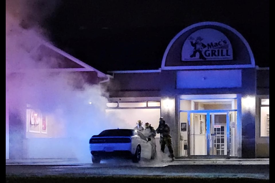 Fire crews work to put out the flames of a car parked outside the restaurant at Lac La Biche's Almac Hotel.