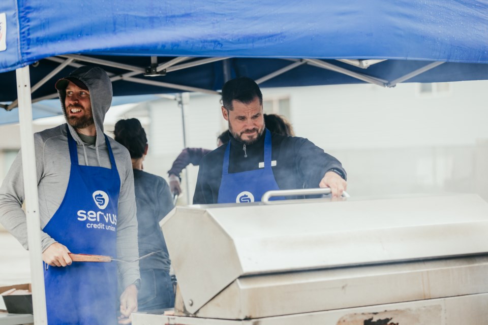 Staff members cook burgers at the parking lot near Servus Credit Union on Aug. 28.