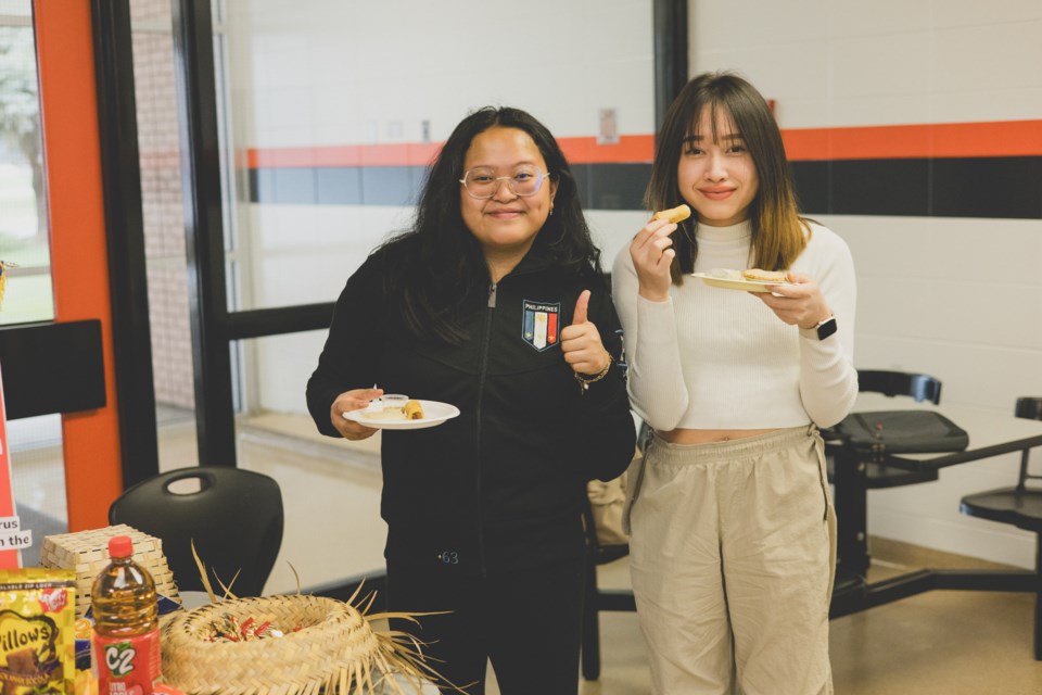 Students, staff and parents serve food during the St. Paul Regional High School multicultural day. Pictured: Aira Aguilor and Earn Phonthep check out the Philippines display.