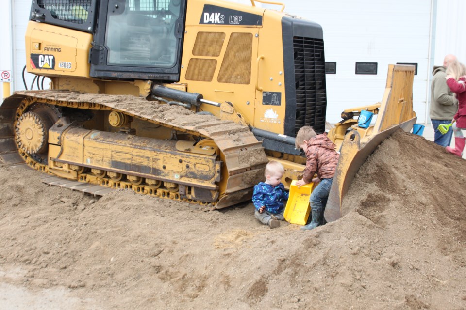 Children play near a dozer in some sand at the MD of Bonnyville public works open house.