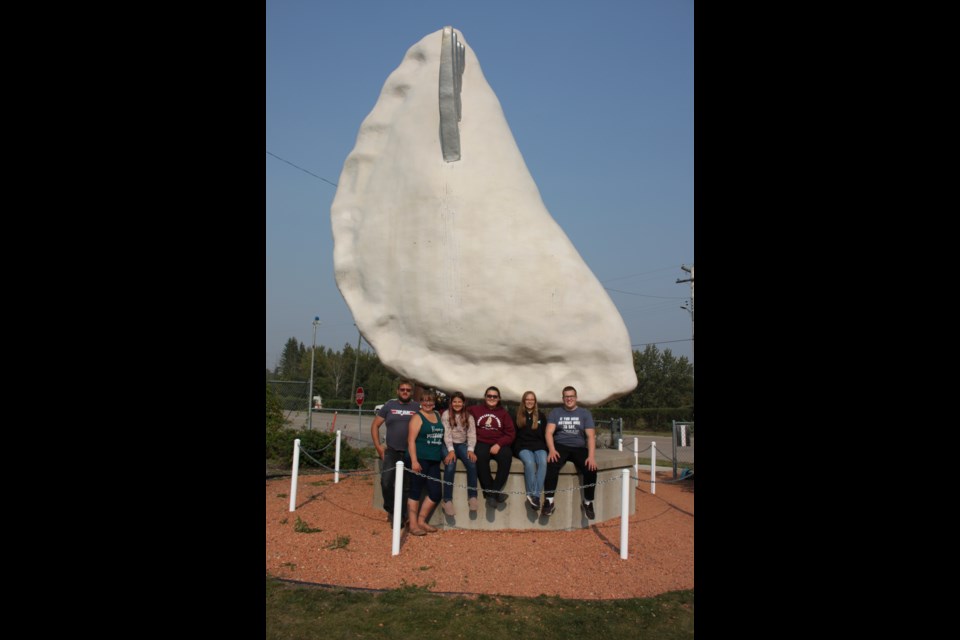 Youth Pyrogy eating contest winner Natasha Tkachuk sits underneath Glendon's iconic Pyrogy sculpture with her family. From the left Wayne Tkachuk, Marcella Tkachuk, Jenna Tkachuk, Natasha Tkachuk, Ashlyn Tkachuk, and Dawson Tkachuk.