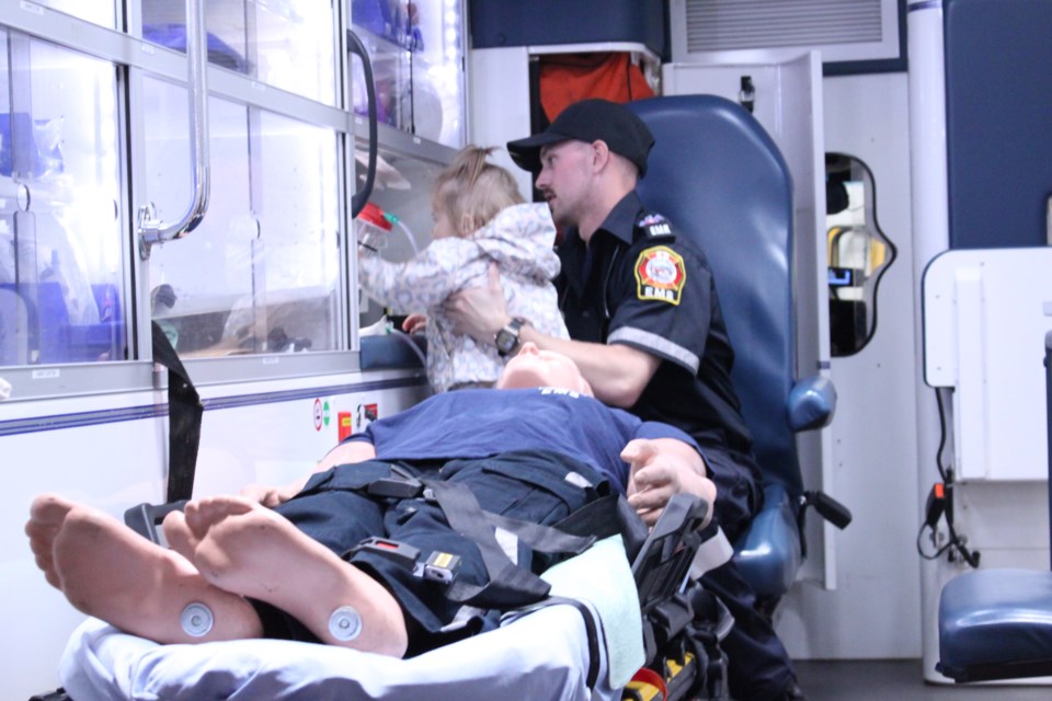 Brayden Audet, EMR, helps a young girl explore the ambulance.