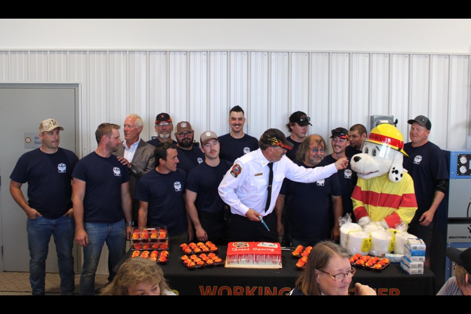 Several volunteer firefighters of the Station 8 Ardmore cut the grand opening cake with Station 8 Fire Chief Derek Neumann and Sparky.