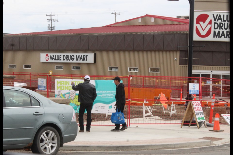 Two men walk past the Main Street Mondays sign and into the construction area during a quiet Monday afternoon in downtown Lac La Biche.