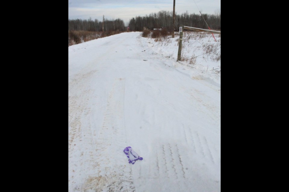 A purple medical glove, tire tracks and discoloured snow mark the entrance to the driveway of a property along the Elinor Lake Road destroyed by a Dec. 5 fire. A Westlock man is facing charges in connection to the blaze.