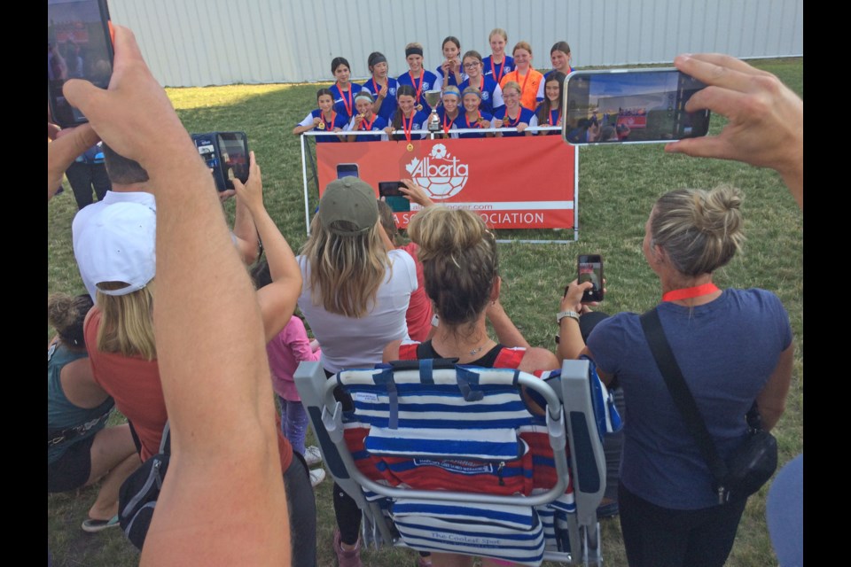 The Lakeland FC U13 girls celebrate with the trophy, gold medals and family at the Sunday's presentation ceremony in Camrose of the Tier 3 Alberta Soccer Association championships.