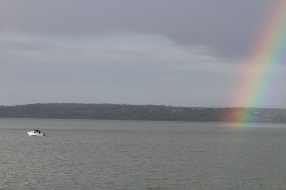 A white fishing boat trolls near the shoreline of Sir Winston Churchill Provincial park – and also near the end of the rainbow – on Lac La Biche lake during a brief wind and rain storm on Friday afternoon. 