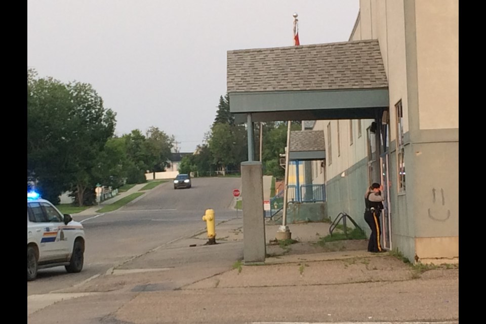 A Lac La Biche RCMP member looks through the front doors at Ecole St. Catherine on Saturday night. Police were responding to an alarm call at the school on 103 Street at about 9pm on Saturday.