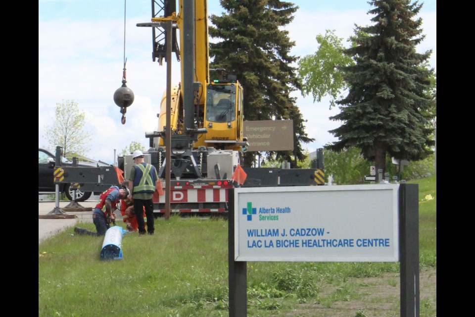 Crews work with equipment to lift new infrastructure onto the W. J. Cadzow Hospital - part of a $3 million power upgrade.