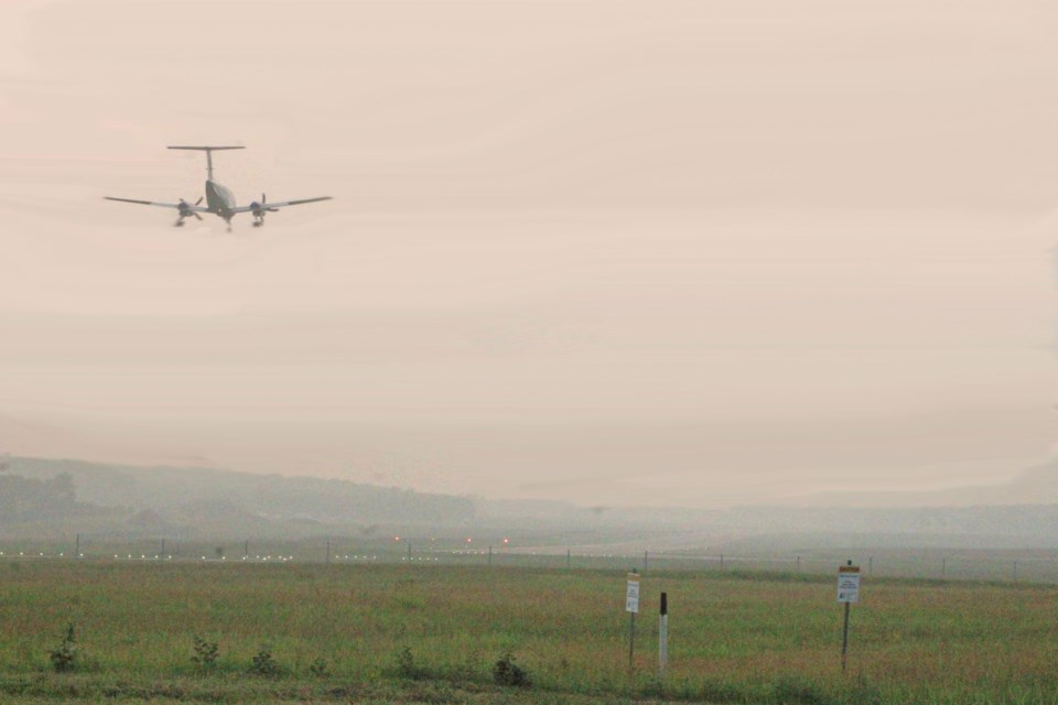 A plane approaches the runway of  the Lac La Biche Airport for a smoky afternoon landing.