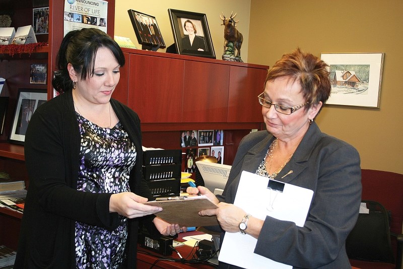 Genia Leskiw (right), MLA for Bonnyville &#8212; Cold Lake, adds her name to the petition presented by Crystal Gliege (left) and Corita Vachon (not pictured) signed by over