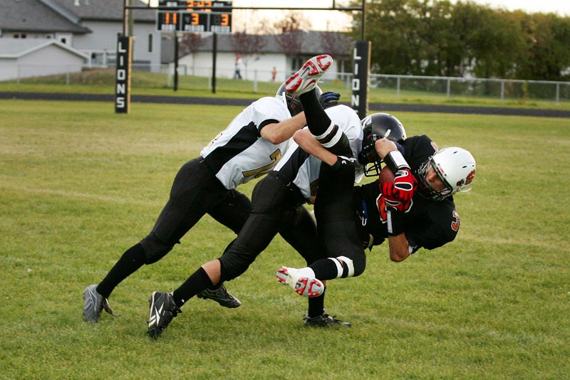 A couple of Royals football players tackle Mark Proskiw (3) after he caught a pass during the second half of the game between the Lions and Royals at St. Paul on Friday