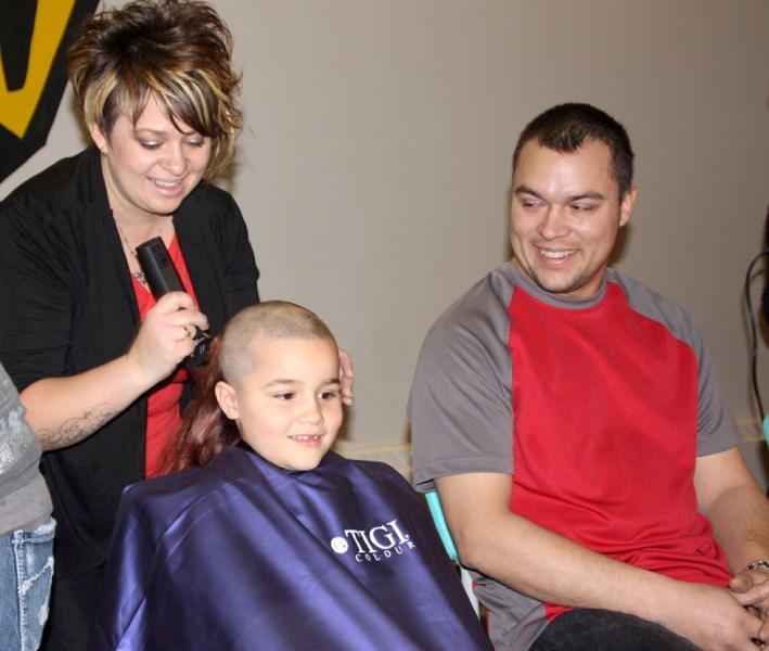 Hairdresser Brandi Whelan from St. Paul wields a buzzer to shave the locks of her niece Trinity Marsh, while Trinity&#8217;s father Dan waits for his turn. Seven-year-old