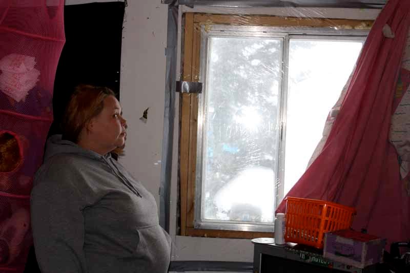 Lisa Desjarlais stands in front of windows in her rented mobile home, which she said are covered with frost and ice on cold days.