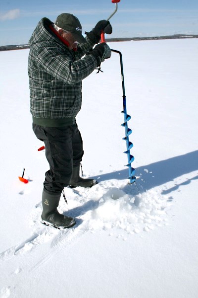 Chuck Ouellette drills a hole into the ice on the east side of Vincent Lake to check for signs of a possible fish kill on Saturday. Ouellette said it took years for the fish