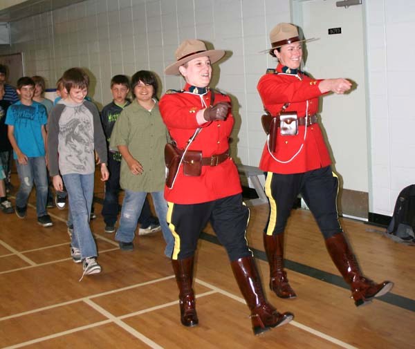 Students march into the Racette School gym behind RCMP constables Tammy Protasiwich and Danielle LaRoche for the DARE graduation ceremony on Thursday.