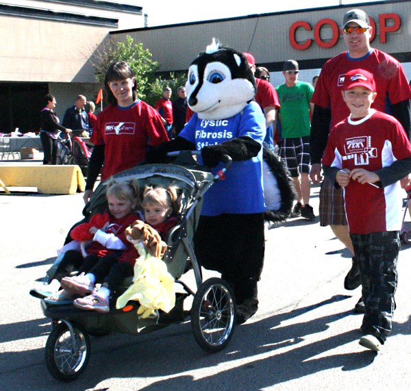 Skelly the skunk, mascot for Cystic Fibrosis Canada, pushes Madison and Haley at the start of the Great Strides walk from the Co-op Mall on Sunday. From left: Chantal