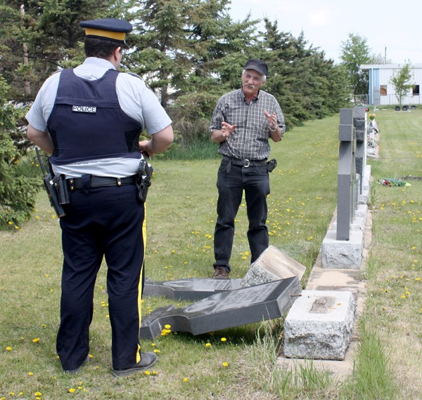 Dionnis Poulin, caretaker of the St. Paul cemetary, reports to Cst. Bretton about 20 headstones, which were damaged in late May.