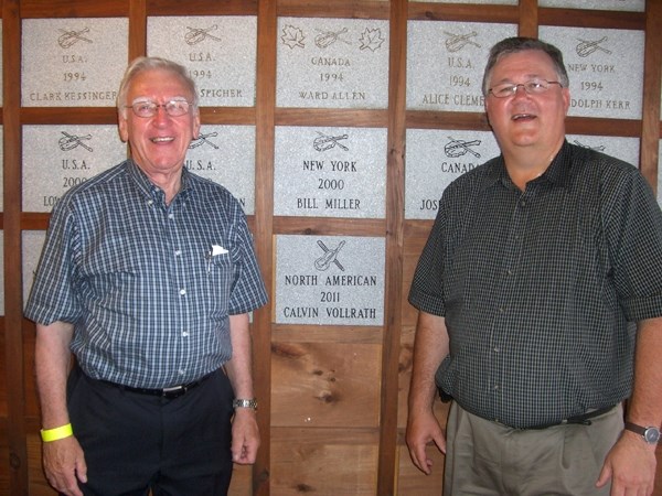 Jim Hickey and Calvin Vollrath stand in the North American Fiddlers&#8217; Hall of Fame in New York State where Vollrath&#8217;s name hangs alongside legendary fiddlers.