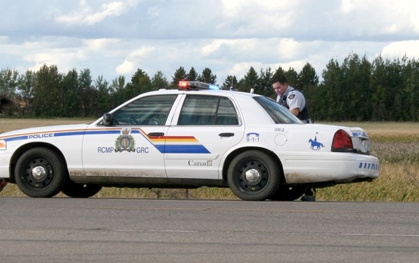 An RCMP officer assists a man lying on the side of Highway 29 on Sept. 16, while a woman who stopped to help goes back to her vehicle.