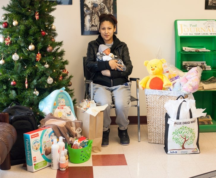 Kylee Houle holds her son, Geovanni, while surrounded by an assortment of gifts donated by local businesses. Not pictured is Geovanni&#8217;s dad, Conrad Quinney.