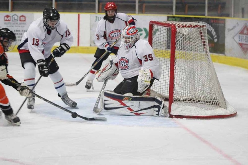 St. Paul Midget goalie Jaden Saik turns away a shot, while teammates Sam Zalaski (#13) and Logan Hellquist (#3) try to lend a hand.