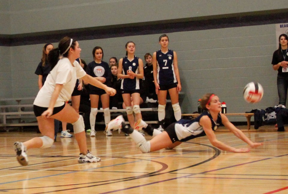 école Beaséjour Lynx player Ashley Menard goes for a tough dig as her teammates watch the play.