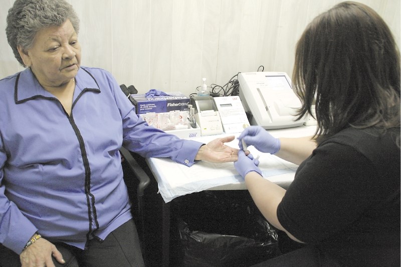 Mindy Kowal, a lab tech with the Mobile Diabetes Screening Initiative, administers a blood sugar test to Lorraine Laboucane at the Métis Region 1 office. The MDSi team was on 