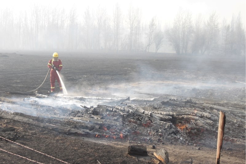 A member of the Boyle Fire Department hoses down a hot spot near a home that was evacuated due to an out-of-control wildfire on Sunday.