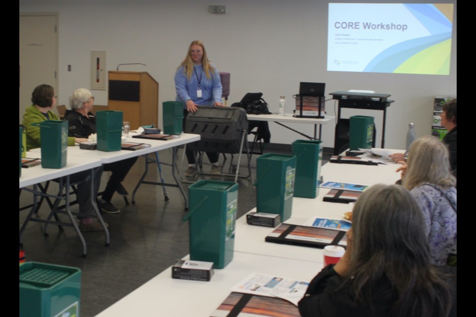 Julia Shapka goes over the basic functions of a compost tumbler with some of those who attended the workshop. Chris McGarry photo.