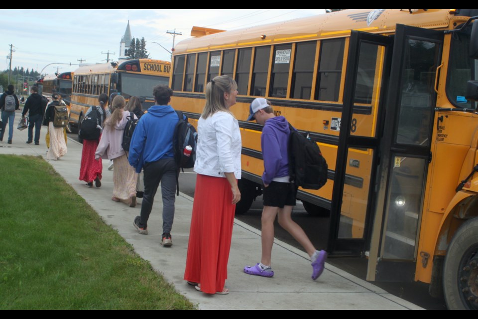 Karen Grygus, principal of École Plamondon School, greets students as they get off the bus on Tuesday, Sept. 3 for the first day of classes at the school since April 18. The school was closed for the remainder of the last school year following a flood that caused extensive damage to the building. From April-June, students at the school attended their classes at temporary venues in Plamondon and Lac La Biche. Chris McGarry photo.