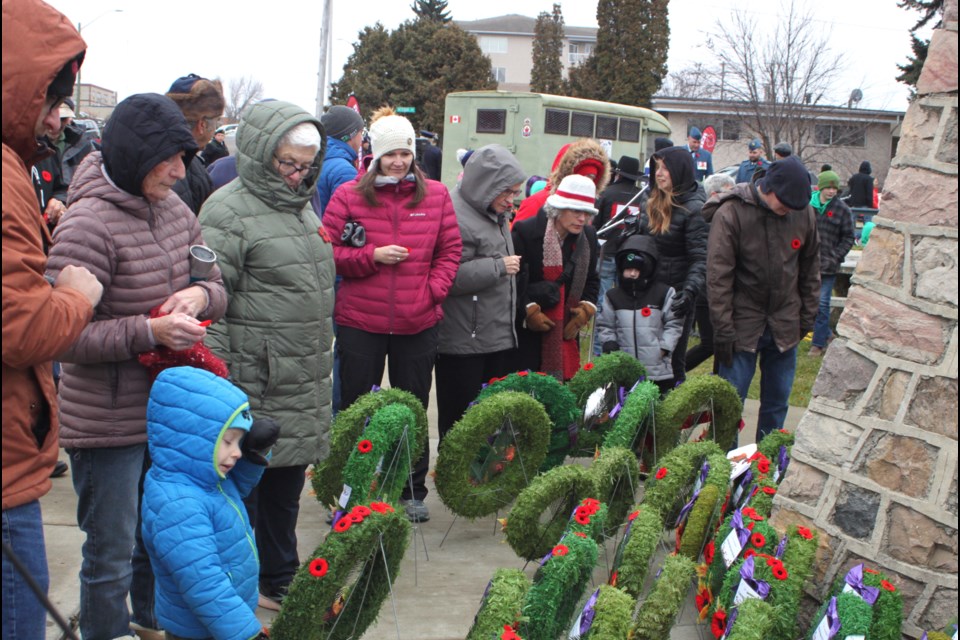 People place poppies on wreaths at the end of the ceremony. Chris McGarry photo. 