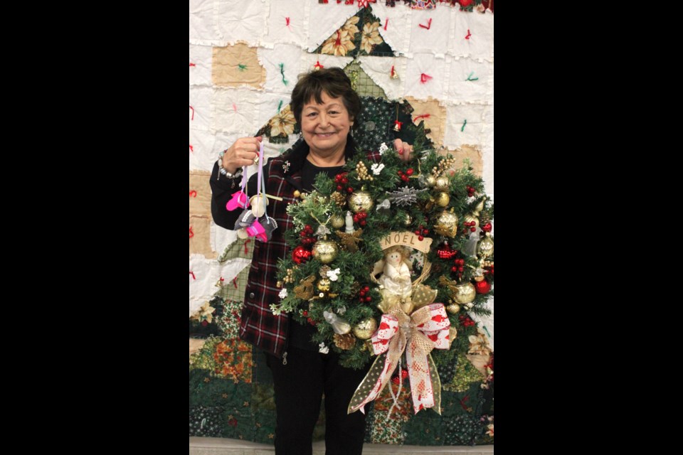 Mary Lehoux stands with a few pairs of miniature slippers and a colourful Christmas wreath that she made. Chris McGarry photo. 