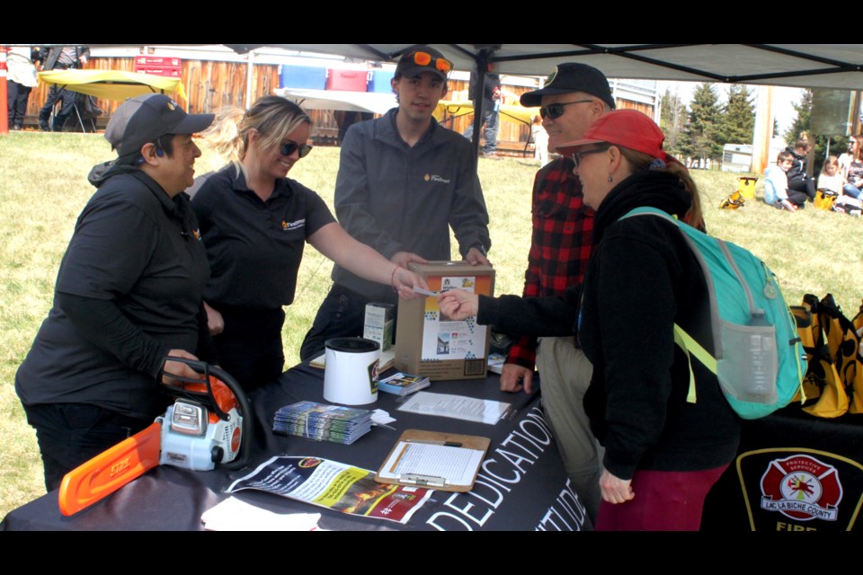 Lori A. Lemay, Angelica Webb, and Lyric Jesso, members of Lac La Biche County Fire Rescue, talk with Mike and Heather Dempsey about the FireSmart program. Chris McGarry photo.