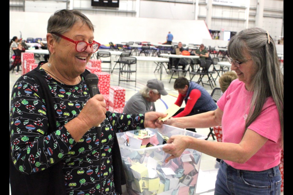 Pat Boon-Anderson, co-founder of the Festival of Trees who helps to organize the popular community event each year, draws a name from a plastic container filled with raffle tickets held by Carol St. Jean. Chris McGarry photo.