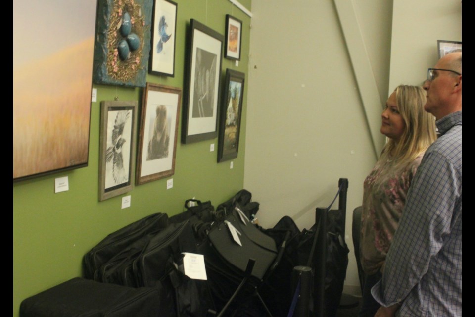 Melanie Braund, an artist from the Lac La Biche region, and Portage College Fine Arts instructor Pierre Oberg, look over the paintings and other pieces of art on display during the grand unveiling of the Lac La Biche County Libraries' art circulation collection, which took place on Thursday, Sept. 19. Chris McGarry photo. 