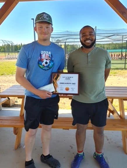 Tanner Davidson-Sykes, an alumni of Lac La Biche FC who now plays with the Portage College Voyageurs men's soccer team, receives an award from Kika Mukininwa, a member of the club executive for Lac La Biche FC, during the season wrap-up event. Submitted photo.  